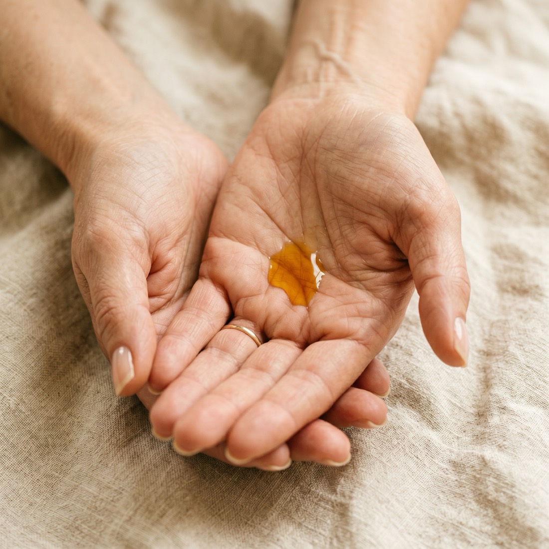 Hands receiving a drop of golden Sacha Inchi oil